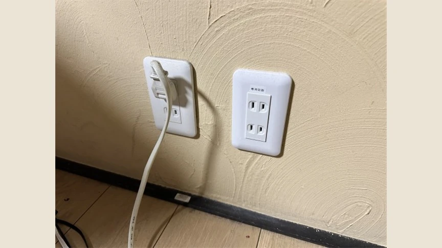 床近くに設置された壁のコンセントと電源コード