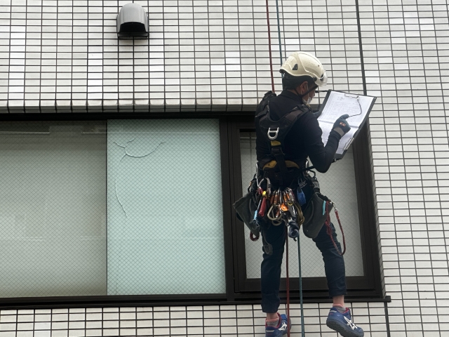 池松ビルでロープによりタイル外壁を打診調査する技術者