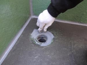 ベランダのドレン排水口まわりをコーキング処理している写真